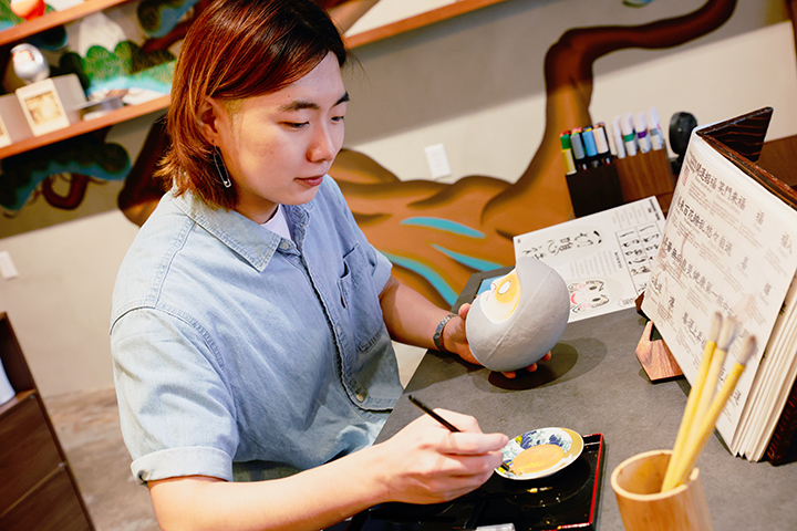 專注地用毛筆描繪設計圖的情景